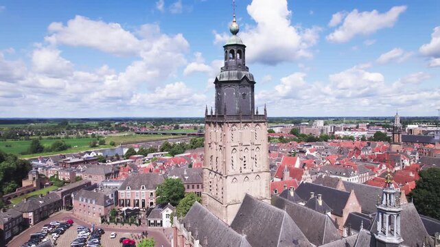 Reveal of central square in Hanseatic medieval town Zutphen, The Netherlands with Walburgiskerk church rising above historic city against a blue sky. Aerial picturesque Dutch city