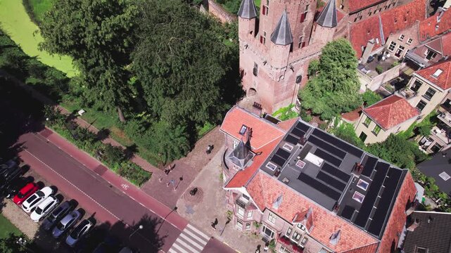 People on the street below of Drogenaps city entrance tower in Zutphen, The Netherlands, historic city wall against a blue sky. Picturesque Dutch city