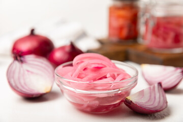 Pickled onions in a glass jar on the table. pickled red onion. Vegetarian spicy dish. Delicious homemade marinated pickled purple onions . Space for text. Copy space.