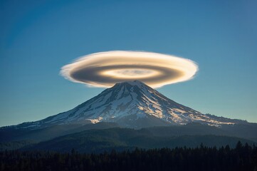 A lenticular cloud emphasizes the summer season over a mountain peak.