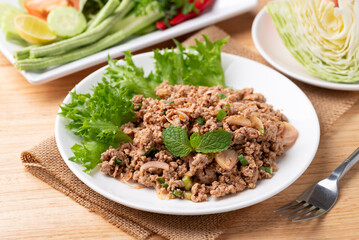Local Thai food, Spicy minced pork salad (Larb Moo) eating with fresh vegetables on wooden background