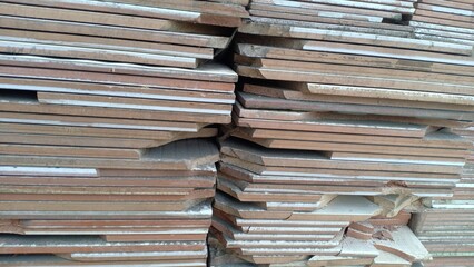 A collection of used ceramic tiles neatly arranged in a wooden box. The tiles vary in color, texture, and pattern, showing signs of wear that add character and history. This scene reflects recycling a