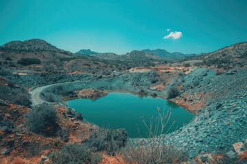 Obraz premium Deserted pyrite excavation site with a lake filling the pit and mountainous waste piles