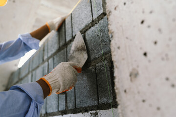 A skilled bricklayer works with mortar and trowel, carefully building a brick wall at a construction site with strength and precision.