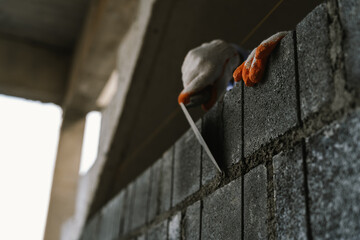 A skilled bricklayer works with mortar and trowel, carefully building a brick wall at a...