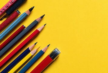 A collection of colored pencils in a diagonal composition on a vibrant yellow background, with room for text or graphics on the right