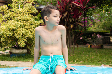 A curious Colombian boy looks to the right while sitting on the edge of a pool in Rivera, Huila,...