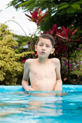A Hispanic boy making a funny face while enjoying a swim in a hotel pool in Rivera, Huila,...