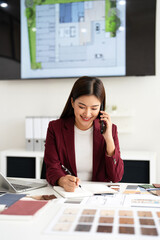 Happy interior designer speaking over the phone in her home office. Creative business woman taking...