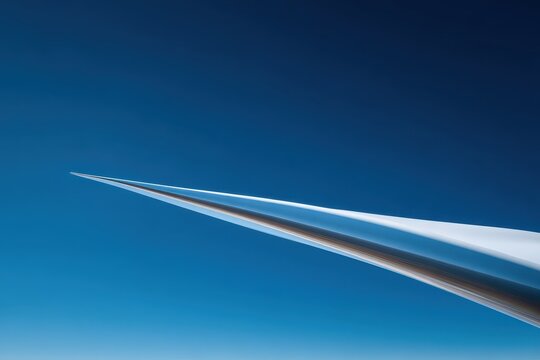 Supersonic aircraft's sharp, reflective nose cone pointing into a vast, clear blue sky.