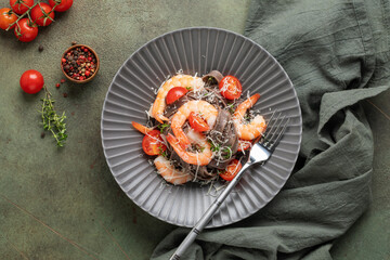Homemade black tagliatelle noodles with prawns, tomatoes and cheese in a bowl on the table. Top view