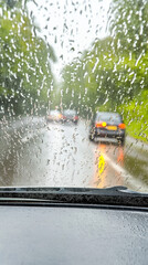 Rain streams down the car windshield, blurring the outside world.