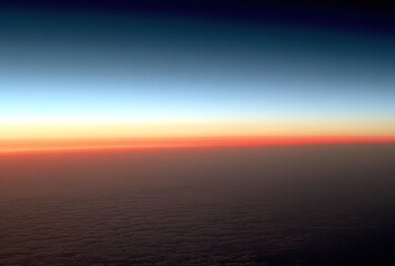 Obraz premium A scenic aerial shot of a sunrise or sunset, with a colorful horizon and a blanket of clouds below, evoking a sense of peace