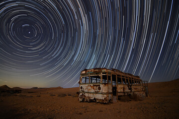 abandoned bus in the desert with star trails