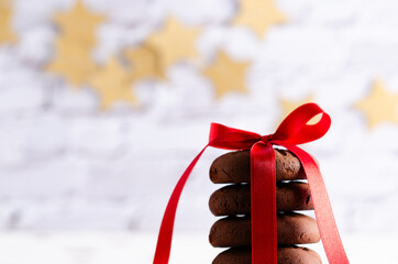Stacked chocolate cookies tied with a red ribbon and a garland of golden stars at the back....