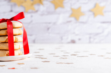 Cropped stacked vanilla cookies tied with a red ribbon and a garland of golden stars at the back....