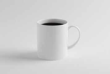 A white mug filled with dark liquid sits on a white surface, casting a soft shadow in a minimalist setting