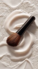 Cosmetic brush rests on swirls of light, creamy product, textured background. Warm, inviting