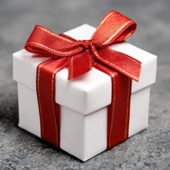 Gift box with red and gold ribbon on textured gray surface, centered and brightly lit