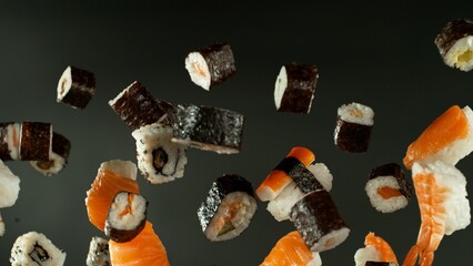 Freeze motion of flying sushi pieces on black background. Concept of flying japanese traditional...