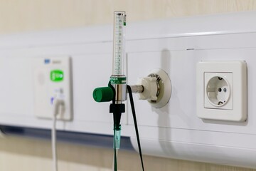 Medical oxygen cylinder regulator and nurse call button system mounted on wall panel above hospital...