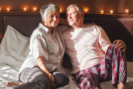 Happy elderly couple wakes up in bed in the morning - Powered by Adobe