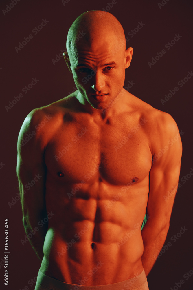 Poster muscular man posing dramatically in low light, showcasing impressive physique and intense expression