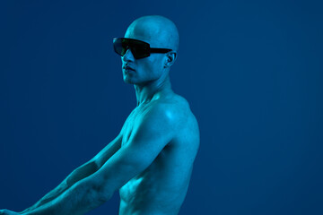 Confident man in sunglasses poses against a blue background. The image captures a striking black...