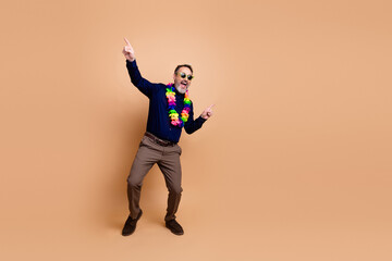 Playful businessman wearing colorful lei necklace against beige background with enthusiastic pose...