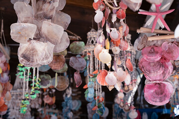 Colorful hanging shells in a beach market with sunlight and soft blur background © marta