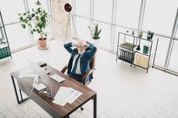Professional mature businessman taking a break in a modern bright office surrounded by paperwork and stylish decor