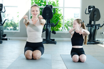 A young woman and a girl are exercising at the fitness center, reflecting the concept of fitness.
