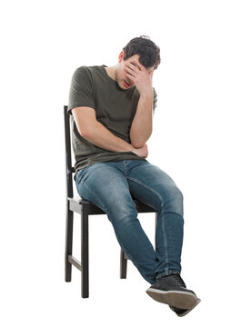 Disappointed and pessimistic young man sitting on a chair covering face with his palm. Desperate guy seated alone suffer anxiety, distress depression feeling, full length portrait isolated