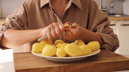 A woman is focused on cutting fresh potatoes into pieces. She works meticulously at her kitchen counter, surrounded by kitchen tools and ingredients. The preparation highlights her culinary skills
