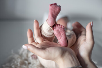 Close-up of newborn baby's little feet and hands in loving mother's hands.