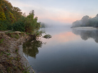 Obraz premium Scenic view of beautiful sunset or sunrise above the pond or lake at autumn or early morning with mist