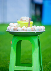  A vibrant display of boiled chicken eggs in an aluminium tray pan served with grounded blended pepper saurce on green plastic chair. A beloved Ghanaian street food snack delicacy. Kosua ne meko