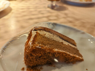 A delicious slice of mocha cake on a plate in a wooden table