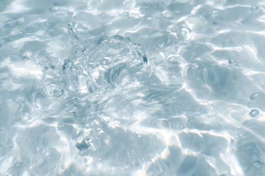 Blurred transparent water surface with bubbles and splashes, soft and clear texture. Modern abstract natural backdrop with sunlight reflections and space for text.