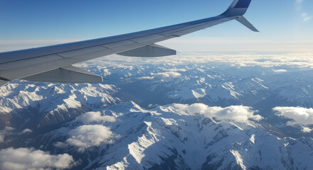 Obraz premium Airplane wing above snowcapped mountains and clouds
