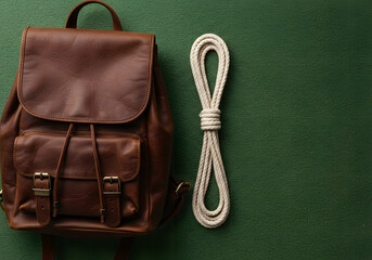 Leather backpack and rope on green surface concept