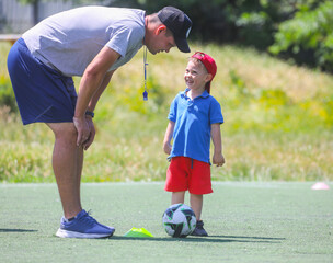 Coach with little  boys learning in football school