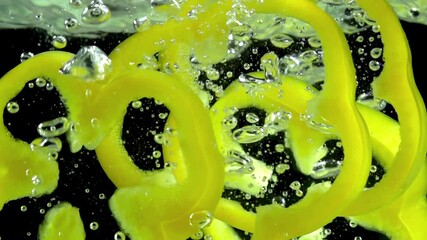 Slices of Yellow Pepper. Yellow pepper slices fall on the water line on a black background. Slow Motion - Powered by Adobe