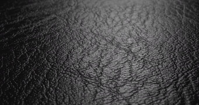Black Leather Surface. Video featuring a smooth, sweep across a textured black leather backdrop, suited for premium visuals.	