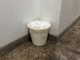Overflowing wastepaper basket in the corner of a room