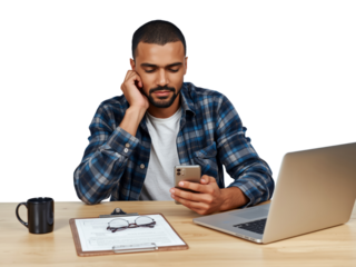 Pensive professional utilizing a mobile device while working remotely with a laptop in sight with