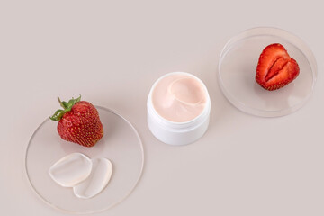 a jar of hand or face cream, strawberries and cream samples on a beige background