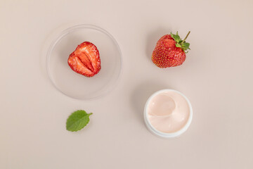 close-up of collagen cream in an open jar and strawberries on a beige background