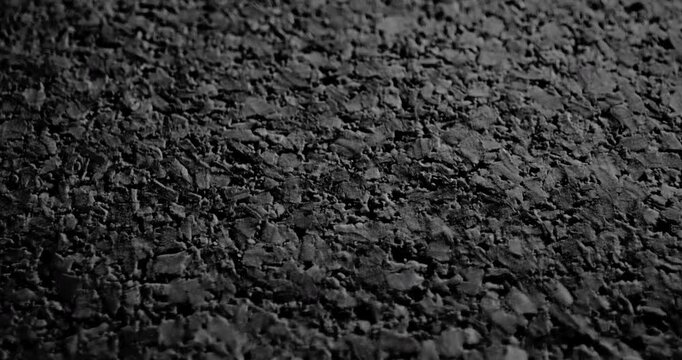 Dark Granular Surface in Motion. Video showing smooth linear movement across a textured black surface with rough granular details