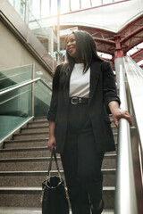 Smiling businesswoman ascending stairs in modern building